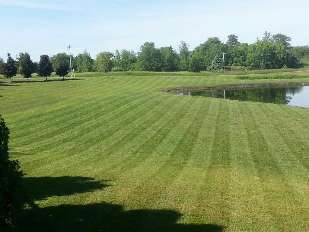 Freshly striped lawn along a pond mowed by Jay's Lawn Service in Angola, IN